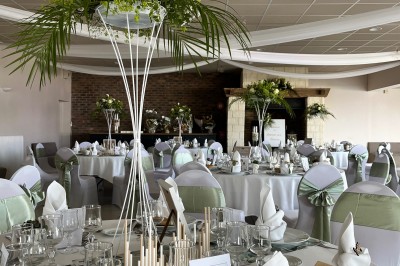 Table ronde élégamment dressée avec vaisselle, couverts, serviettes roses et centre de table floral coloré.