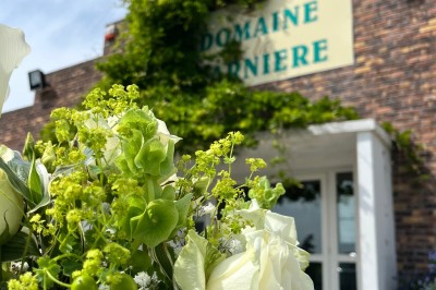 Table ronde élégamment dressée avec vaisselle, couverts, serviettes roses et centre de table floral coloré.