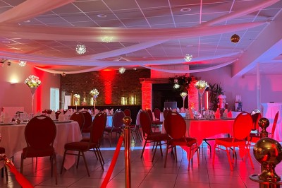 Table ronde élégamment dressée avec vaisselle, couverts, serviettes roses et centre de table floral coloré.