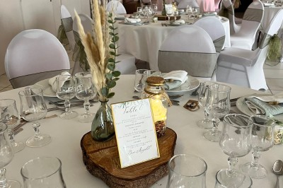 Table ronde élégamment dressée avec vaisselle, couverts, serviettes roses et centre de table floral coloré.