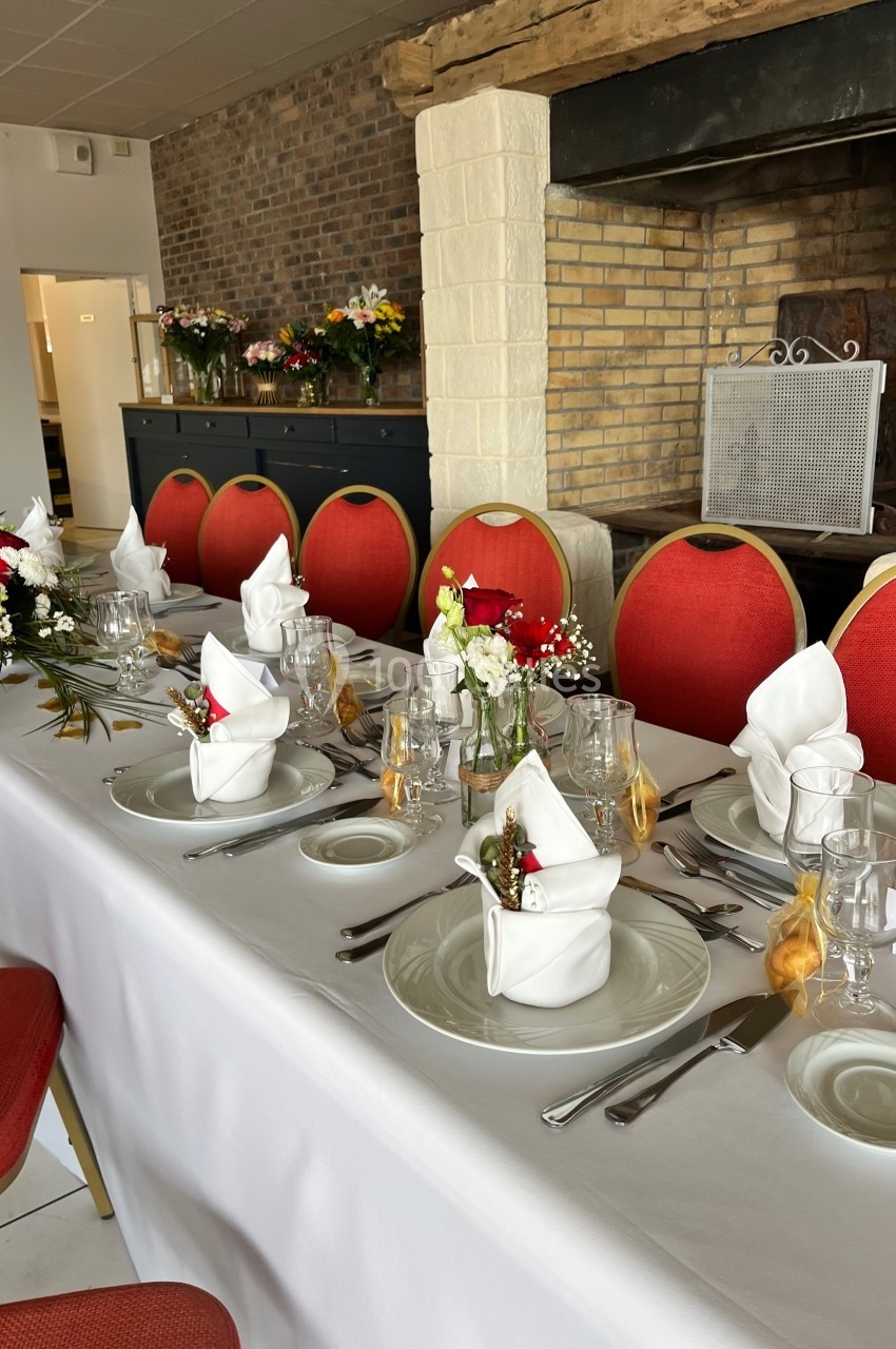 Table dressée pour un repas festif avec nappes blanches, serviettes pliées, vaisselle élégante et décorations florales.