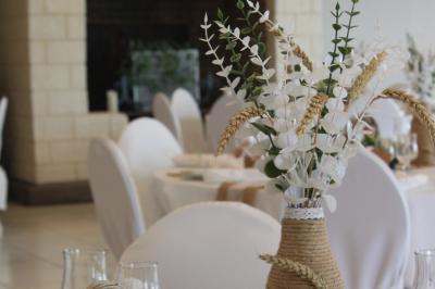 Table ronde élégamment dressée avec vaisselle, couverts, serviettes roses et centre de table floral coloré.