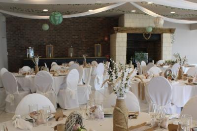 Table ronde élégamment dressée avec vaisselle, couverts, serviettes roses et centre de table floral coloré.