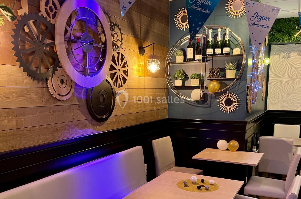 Décoration intérieure d’un restaurant avec engrenages muraux, étagère de bouteilles et ambiance festive d’anniversaire.