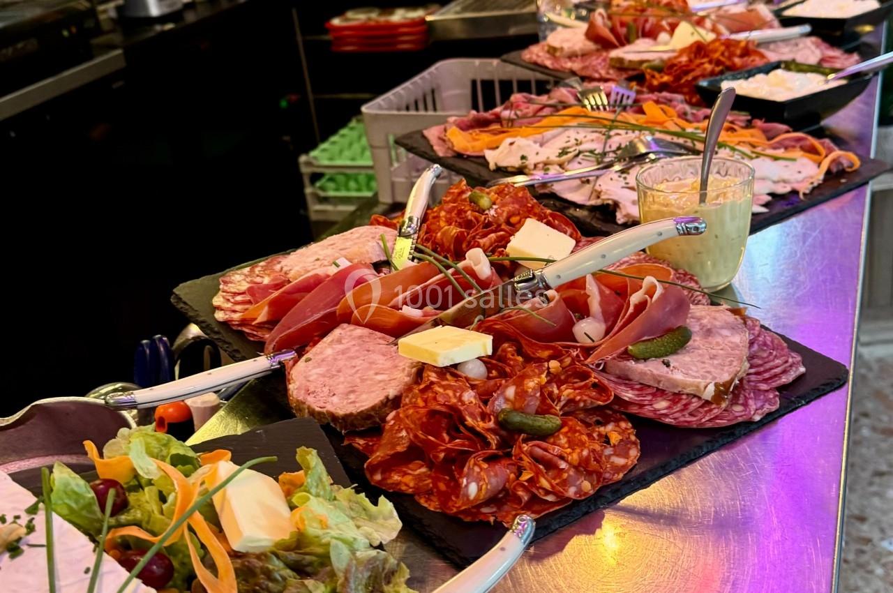 Plateau de charcuteries, fromages et accompagnements disposés sur un comptoir dans un bar ou restaurant.