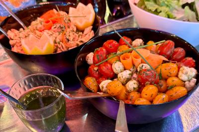 Assortiment de salades dans des bols noirs : salade de pommes de terre, tomates cerises et pâtes au pesto.