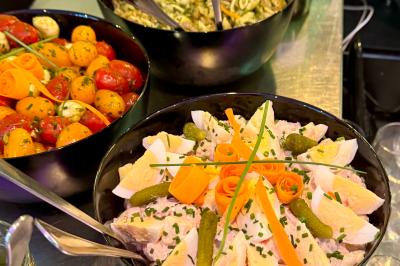 Assortiment de salades dans des bols noirs : salade de pommes de terre, tomates cerises et pâtes au pesto.