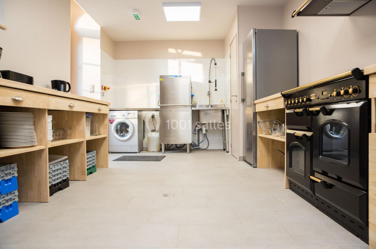 Cuisine fonctionnelle avec électroménagers modernes, plan de travail en bois, lave-linge et évier en inox.