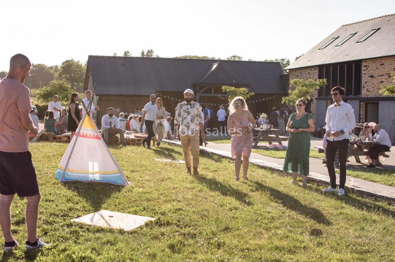 Des personnes participent à une activité en plein air près d'une tente tipi, dans un cadre champêtre et ensoleillé.