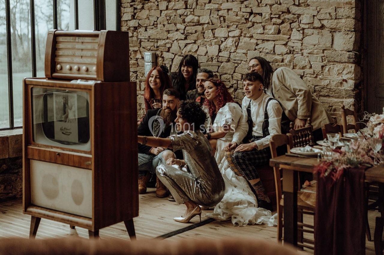 Un groupe de personnes pose devant un téléviseur rétro dans une pièce au mur en pierre.