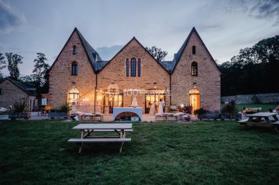 Véranda lumineuse avec murs en briques, grandes baies vitrées noires et vue sur un jardin verdoyant.