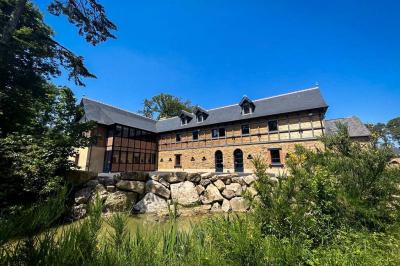 Véranda lumineuse avec murs en briques, grandes baies vitrées noires et vue sur un jardin verdoyant.