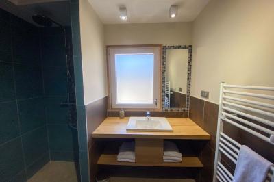 Véranda lumineuse avec murs en briques, grandes baies vitrées noires et vue sur un jardin verdoyant.