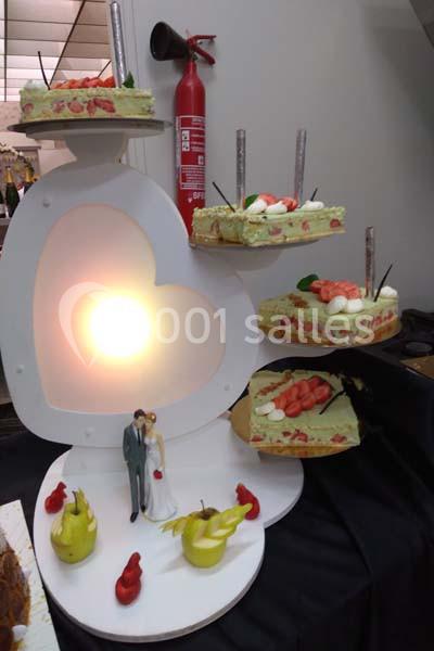 Présentoir de mariage en forme de cœur avec des parts de gâteau décorées de fraises et une figurine de mariés.