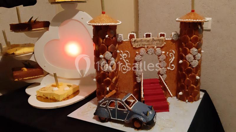 Maquette comestible d'un château en pâte et sucre avec une voiture en gâteau, exposée sur une table.
