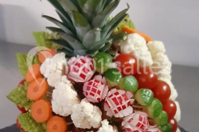 Composition décorative en forme d'ananas réalisée avec des légumes frais comme carottes, radis, tomates et chou-fleur.