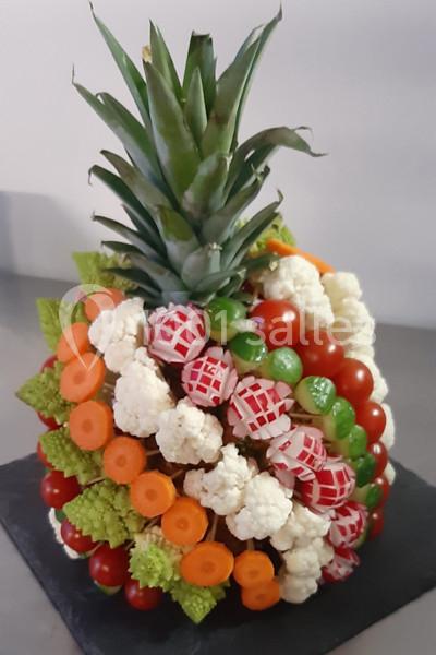 Composition décorative en forme d'ananas réalisée avec des légumes frais comme carottes, radis, tomates et chou-fleur.