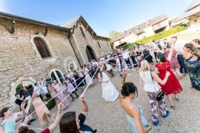 Vue depuis une arche en pierre sur une cour avec des fleurs en premier plan et un paysage champêtre en arrière-plan.