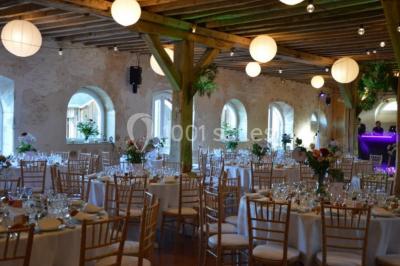 Vue depuis une arche en pierre sur une cour avec des fleurs en premier plan et un paysage champêtre en arrière-plan.