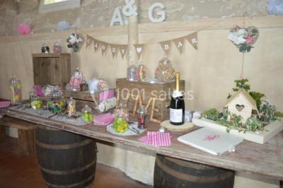 Vue depuis une arche en pierre sur une cour avec des fleurs en premier plan et un paysage champêtre en arrière-plan.