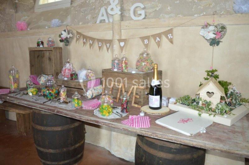 Table décorée avec un candy bar, pots de bonbons, bouteilles et éléments rustiques dans une ambiance festive.