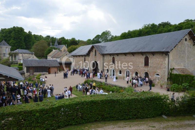 Groupe de personnes rassemblées devant un grand bâtiment en pierre dans un cadre verdoyant.