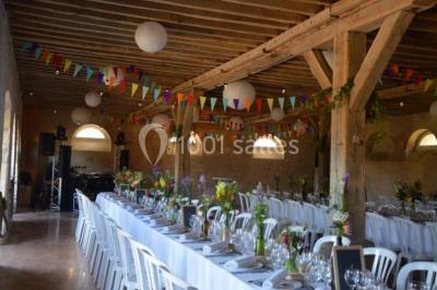 Vue depuis une arche en pierre sur une cour avec des fleurs en premier plan et un paysage champêtre en arrière-plan.