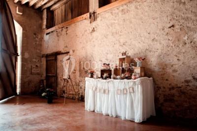 Vue depuis une arche en pierre sur une cour avec des fleurs en premier plan et un paysage champêtre en arrière-plan.