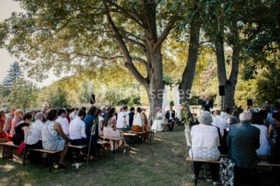 Vue depuis une arche en pierre sur une cour avec des fleurs en premier plan et un paysage champêtre en arrière-plan.