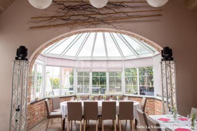 Un couple danse au centre d'une salle éclairée, entouré d'invités assis à des tables.