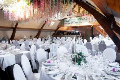 Un couple danse au centre d'une salle éclairée, entouré d'invités assis à des tables.