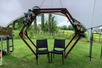 Un couple danse au centre d'une salle éclairée, entouré d'invités assis à des tables.