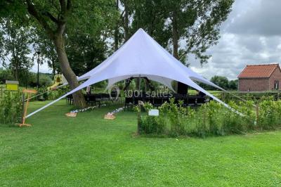Un couple danse au centre d'une salle éclairée, entouré d'invités assis à des tables.