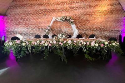 Un couple danse au centre d'une salle éclairée, entouré d'invités assis à des tables.