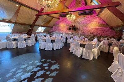 Un couple danse au centre d'une salle éclairée, entouré d'invités assis à des tables.