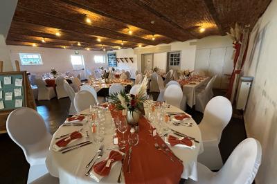 Un couple danse au centre d'une salle éclairée, entouré d'invités assis à des tables.