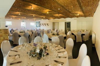 Un couple danse au centre d'une salle éclairée, entouré d'invités assis à des tables.