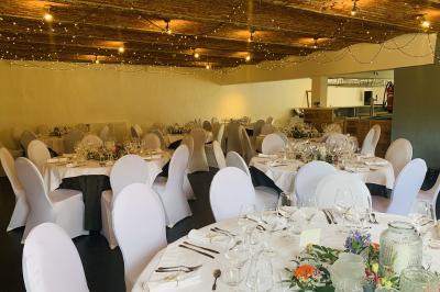 Un couple danse au centre d'une salle éclairée, entouré d'invités assis à des tables.