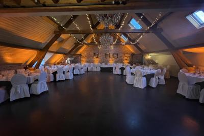 Un couple danse au centre d'une salle éclairée, entouré d'invités assis à des tables.