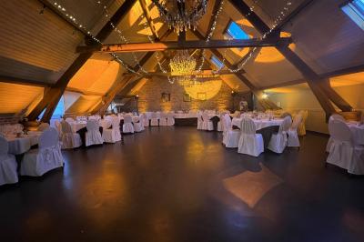 Un couple danse au centre d'une salle éclairée, entouré d'invités assis à des tables.
