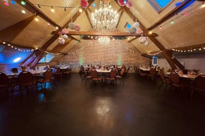 Un couple danse au centre d'une salle éclairée, entouré d'invités assis à des tables.