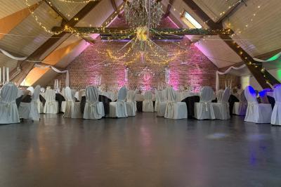 Un couple danse au centre d'une salle éclairée, entouré d'invités assis à des tables.