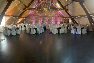 Un couple danse au centre d'une salle éclairée, entouré d'invités assis à des tables.