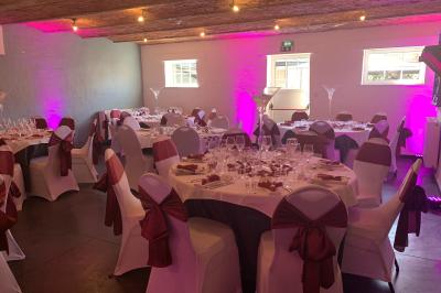 Un couple danse au centre d'une salle éclairée, entouré d'invités assis à des tables.