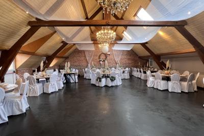 Un couple danse au centre d'une salle éclairée, entouré d'invités assis à des tables.