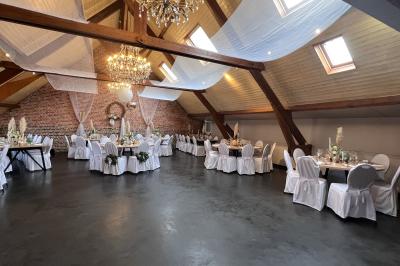 Un couple danse au centre d'une salle éclairée, entouré d'invités assis à des tables.
