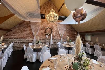 Un couple danse au centre d'une salle éclairée, entouré d'invités assis à des tables.