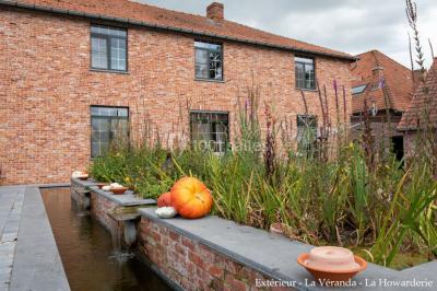 Salle de réunion avec des rangées de chaises face à un écran de projection, sous un plafond en briques apparentes.
