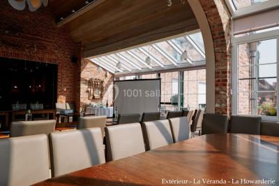 Salle de réunion avec des rangées de chaises face à un écran de projection, sous un plafond en briques apparentes.