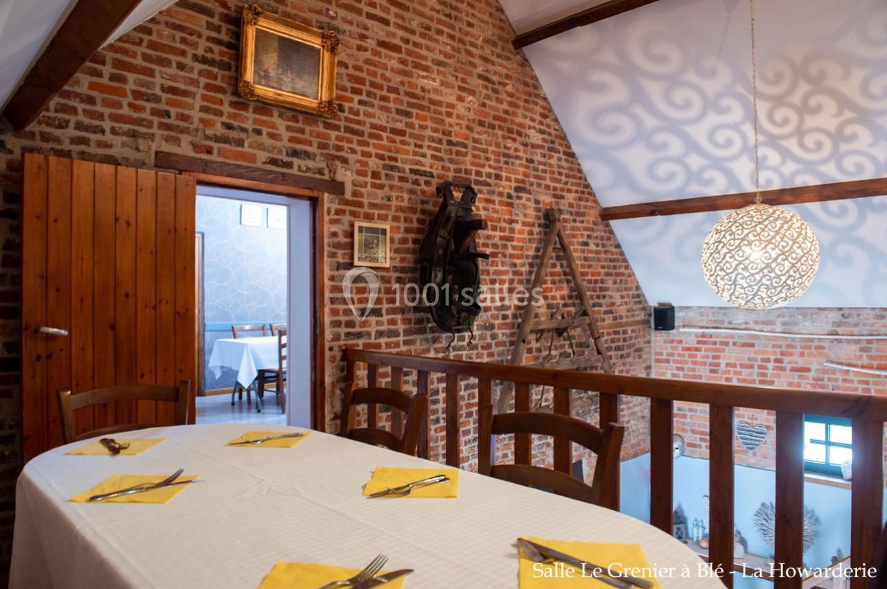 Salle à manger avec murs en briques, table dressée avec nappes jaunes et vue sur une pièce adjacente.